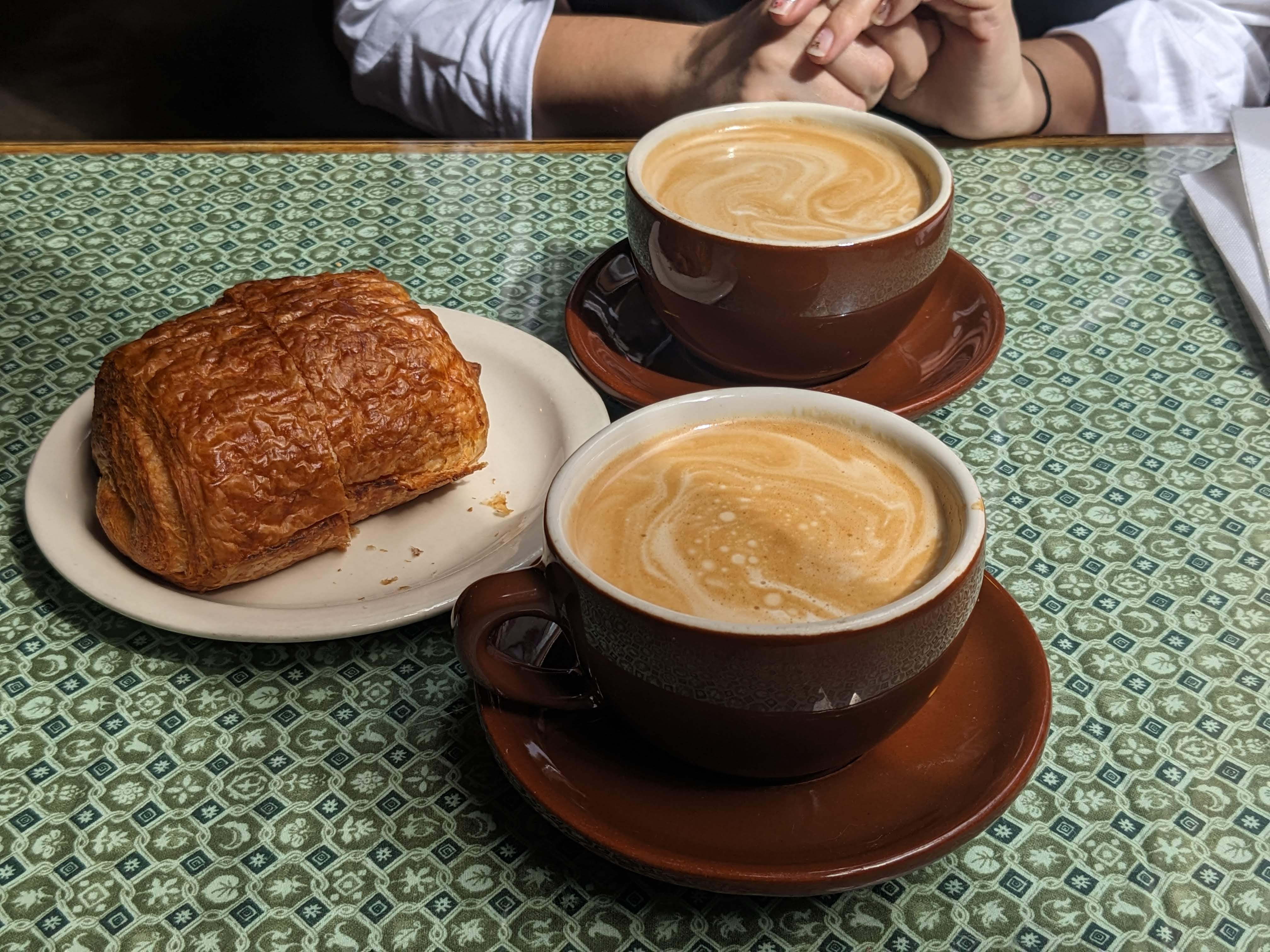 Two cappuccinos and some bread on a table
