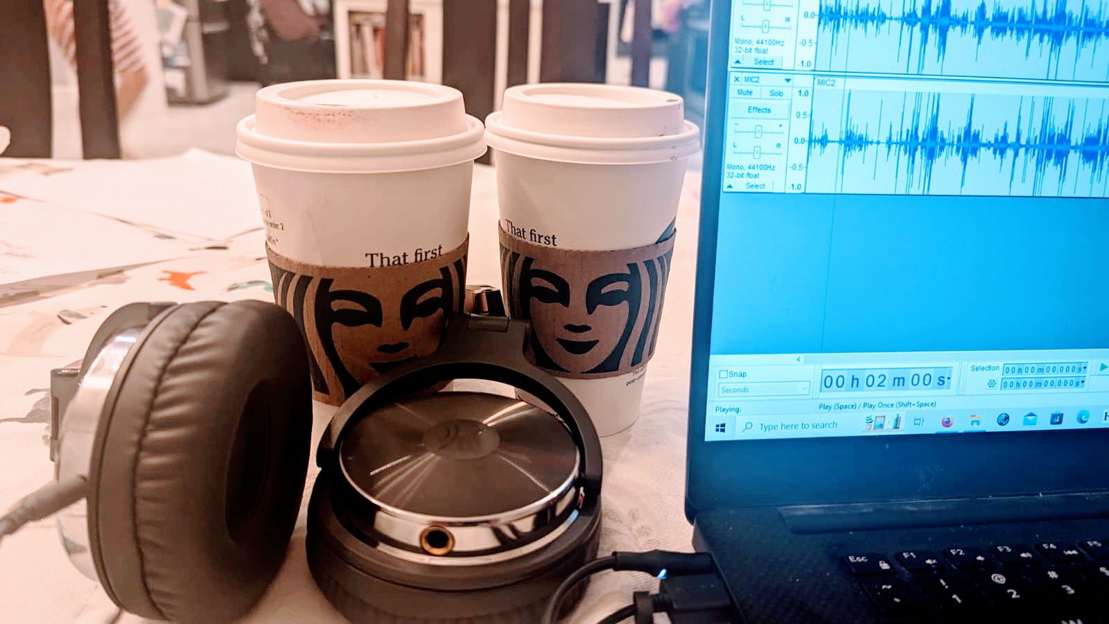 Starbuck’s coffee cups near headset and laptop
